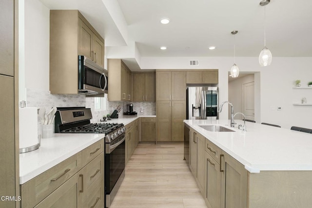 2850 Wagon Wheel Rd Unit 402, Oxnard, CA 93036 - kitchen featuring appliances with stainless steel finishes, light wood-style floors, an island with sink, light countertops, and tasteful backsplash