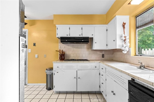 603 Reed Park Dr, Chico, CA 95926 - kitchen with under cabinet range hood, black dishwasher, light tile patterned floors, white cabinetry, and decorative backsplash
