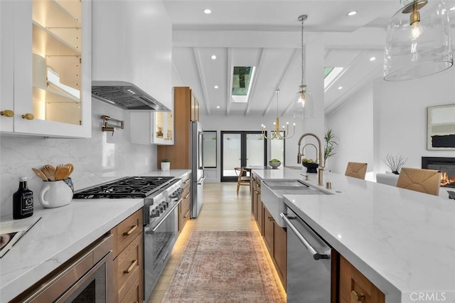 2708 Via Elevado, Palos Verdes Estates, CA 90274 - kitchen featuring appliances with stainless steel finishes, brown cabinetry, wall chimney range hood, backsplash, and glass insert cabinets