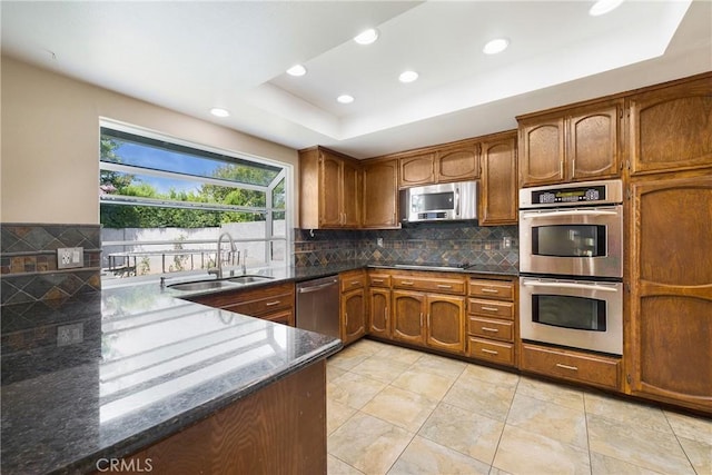 4441 Rustic Rd, Yorba Linda, CA 92886 - kitchen featuring appliances with stainless steel finishes, a tray ceiling, dark stone counters, recessed lighting, and brown cabinets