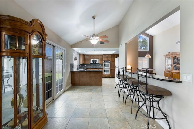 4441 Rustic Rd, Yorba Linda, CA 92886 - kitchen featuring a peninsula, lofted ceiling, stainless steel double oven, dark countertops, and tasteful backsplash