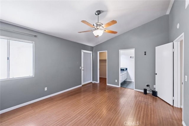 1832 E E Ave J2, Unit 2, Lancaster, CA 93535 - unfurnished bedroom featuring vaulted ceiling, wood finished floors, a walk in closet, ensuite bath, and a ceiling fan