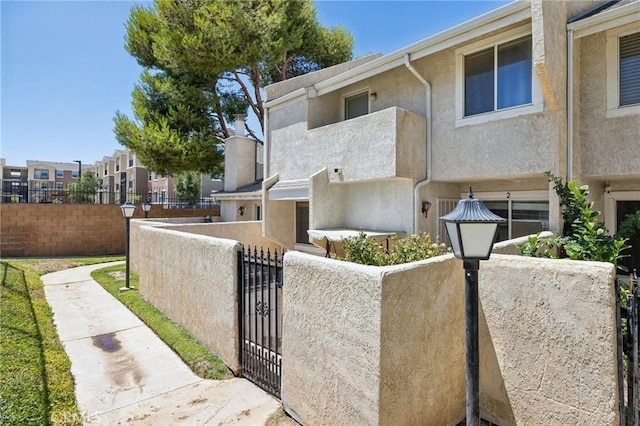 1832 E E Ave J2, Unit 2, Lancaster, CA 93535 - view of front of house with a fenced front yard, stucco siding, a gate, and a residential view