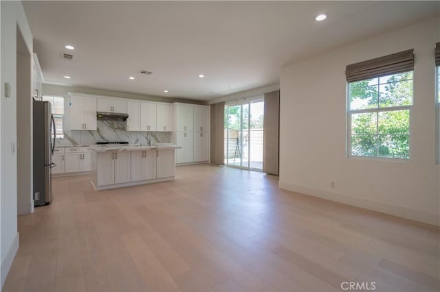 8656 Harvest Pl, Rancho Cucamonga, CA 91730 - kitchen with freestanding refrigerator, light countertops, decorative backsplash, white cabinetry, and under cabinet range hood