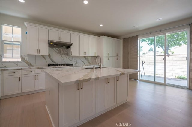 8656 Harvest Pl, Rancho Cucamonga, CA 91730 - kitchen featuring backsplash, white cabinets, under cabinet range hood, light wood-style flooring, and recessed lighting