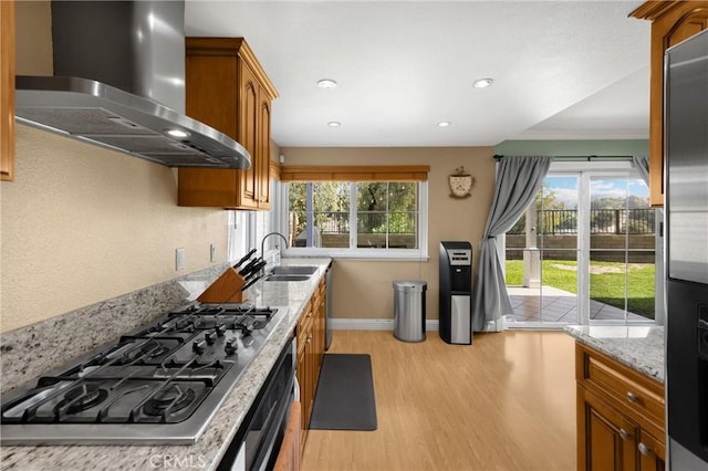2405 E Alicia St, West Covina, CA 91792 - kitchen with wall chimney exhaust hood, stainless steel gas cooktop, light wood-style flooring, brown cabinetry, and light stone counters