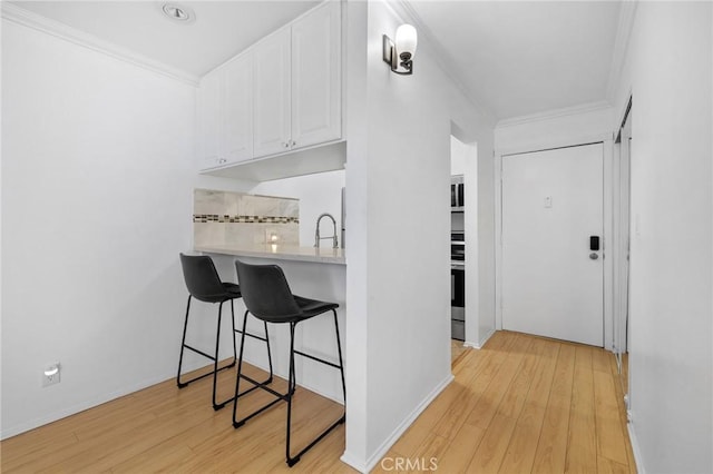 525 S Ardmore Ave Unit 257, Los Angeles, CA 90020 - kitchen with crown molding, white cabinets, light wood-style flooring, light countertops, and a breakfast bar area