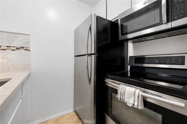 525 S Ardmore Ave Unit 257, Los Angeles, CA 90020 - kitchen featuring stainless steel appliances, white cabinets, light tile patterned floors, and light stone counters