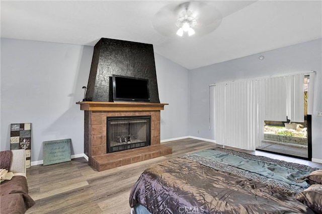 19678 Red Feather Rd, Apple Valley, CA 92307 - bedroom featuring wood finished floors, a tile fireplace, lofted ceiling, and ceiling fan