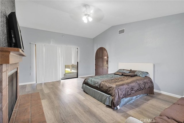 19678 Red Feather Rd, Apple Valley, CA 92307 - bedroom with arched walkways, wood finished floors, vaulted ceiling, a fireplace with flush hearth, and access to outside
