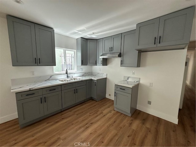 1253 W 65th St, Los Angeles, CA 90044 - kitchen featuring gray cabinetry, under cabinet range hood, light wood-type flooring, and light stone countertops