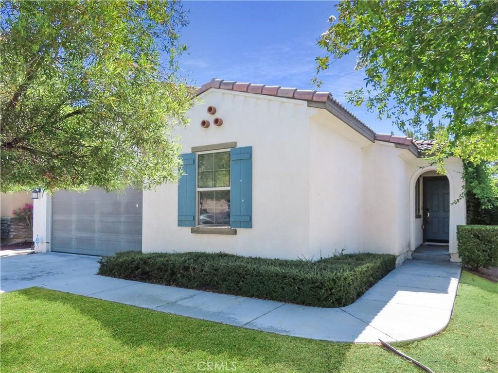 29348 Tournament, Lake Elsinore, CA 92530 - view of side of home featuring stucco siding, a tile roof, concrete driveway, and a lawn