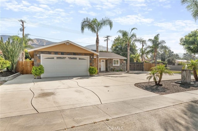 604 Sequoia St, San Bernardino, CA 92407 - ranch-style home featuring concrete driveway, stone siding, an attached garage, and a mountain view