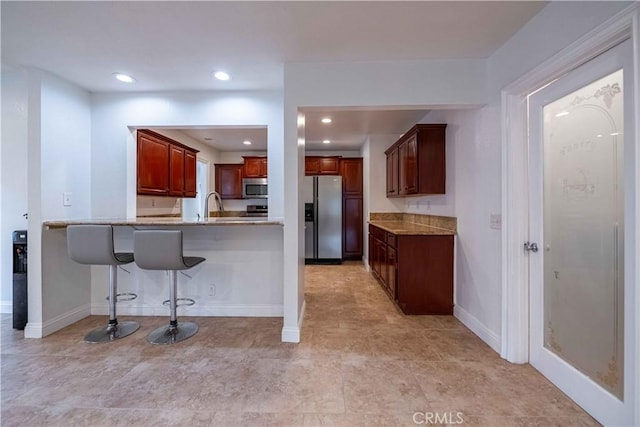 2383 Hampton Ave, Simi Valley, CA 93063 - kitchen with stainless steel appliances, a peninsula, a breakfast bar, recessed lighting, and light stone countertops