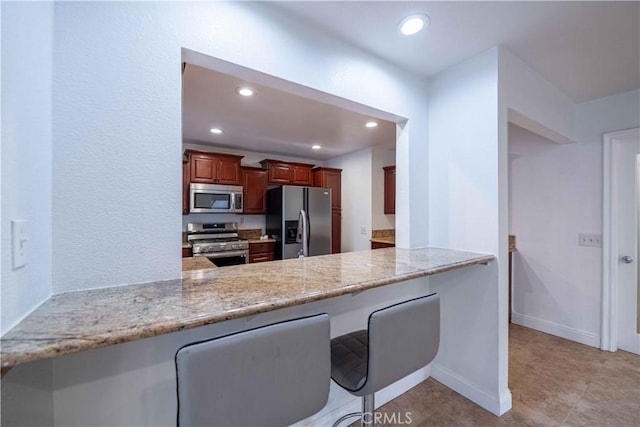 2383 Hampton Ave, Simi Valley, CA 93063 - kitchen with appliances with stainless steel finishes, a peninsula, recessed lighting, a breakfast bar, and light stone countertops