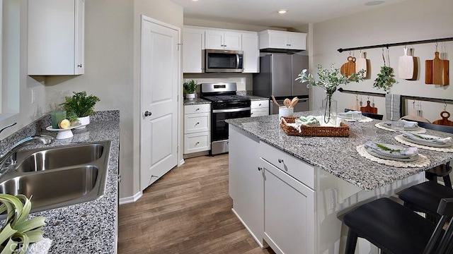 30753 Viper Ct, Winchester, CA 92596 - kitchen featuring stainless steel appliances, a kitchen breakfast bar, white cabinets, wood finished floors, and a kitchen island