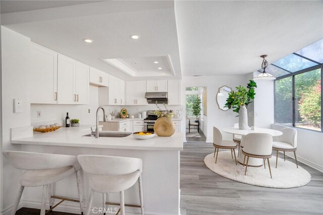 7029 Novara Pl, Rancho Cucamonga, CA 91701 - kitchen with a peninsula, light countertops, light wood finished floors, white cabinets, and stainless steel range with gas stovetop