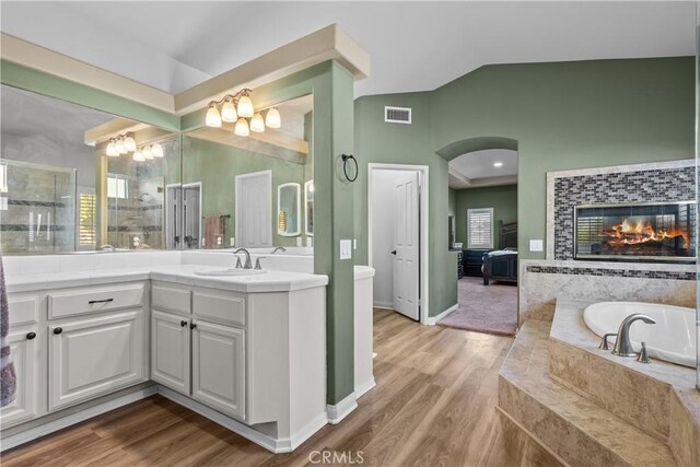 15355 Michael Crest Dr, Canyon Country, CA 91387 - bathroom featuring vaulted ceiling, vanity, a bath, a tile fireplace, and wood finished floors