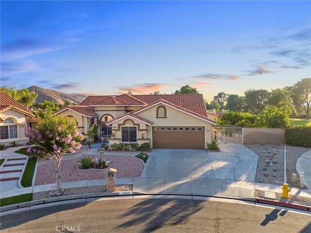 2157 Pecan Tree St, Hemet, CA 92545 - mediterranean / spanish-style home with driveway, stucco siding, a garage, a gate, and a tile roof