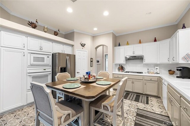 2157 Pecan Tree St, Hemet, CA 92545 - kitchen with white appliances, under cabinet range hood, arched walkways, light countertops, and ornamental molding