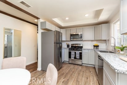 1939 S Broadway, Escondido, CA 92025 - kitchen featuring appliances with stainless steel finishes, gray cabinetry, light wood-style flooring, recessed lighting, and light stone countertops