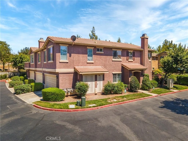 39635 Columbia Union Dr Unit C, Murrieta, CA 92563 - view of front facade with a garage, a chimney, driveway, and stucco siding