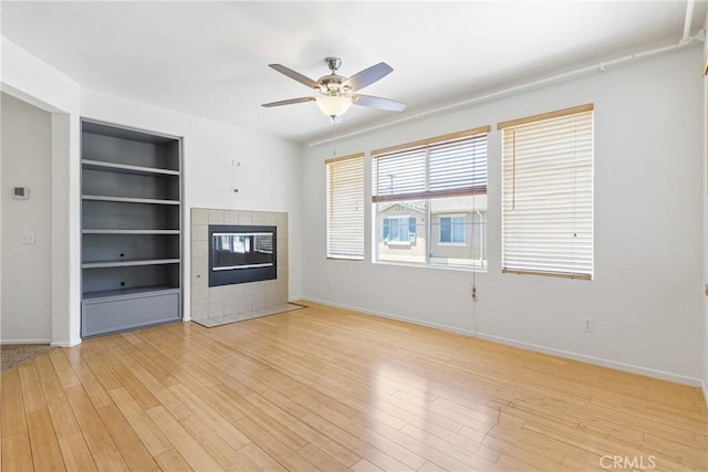 39635 Columbia Union Dr Unit C, Murrieta, CA 92563 - unfurnished living room featuring a tiled fireplace, built in shelves, light wood-style floors, and ceiling fan