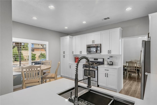 37152 57th St E, Palmdale, CA 93552 - kitchen featuring appliances with stainless steel finishes, wood finished floors, white cabinets, recessed lighting, and light countertops