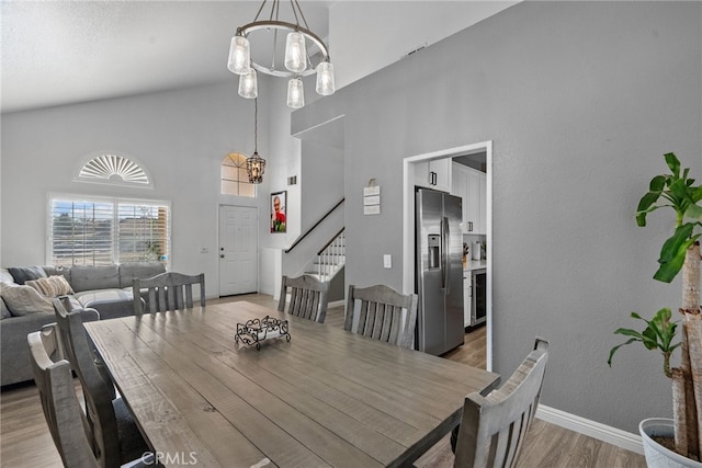 37152 57th St E, Palmdale, CA 93552 - dining space with a chandelier, stairs, light wood finished floors, high vaulted ceiling, and beverage cooler