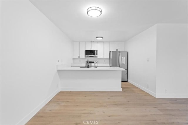 5403 Newcastle Ave Unit 19, Encino, CA 91316 - kitchen with stainless steel appliances, a peninsula, white cabinets, and light countertops