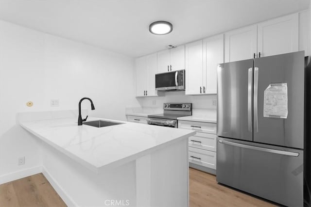 5403 Newcastle Ave Unit 19, Encino, CA 91316 - kitchen featuring stainless steel appliances, a peninsula, light wood-style flooring, white cabinets, and light stone countertops