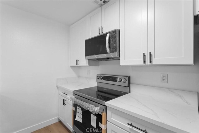 5403 Newcastle Ave Unit 19, Encino, CA 91316 - kitchen with stainless steel range with electric stovetop, white cabinetry, and light stone countertops