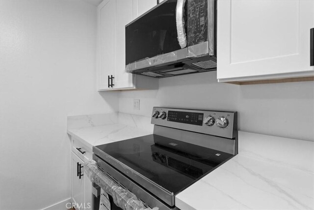 5403 Newcastle Ave Unit 19, Encino, CA 91316 - kitchen featuring appliances with stainless steel finishes, white cabinets, and light stone countertops