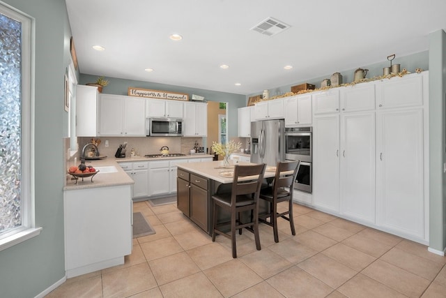 42207 Kimberly Way, Murrieta, CA 92562 - kitchen with stainless steel appliances, white cabinets, light countertops, decorative backsplash, and a kitchen island
