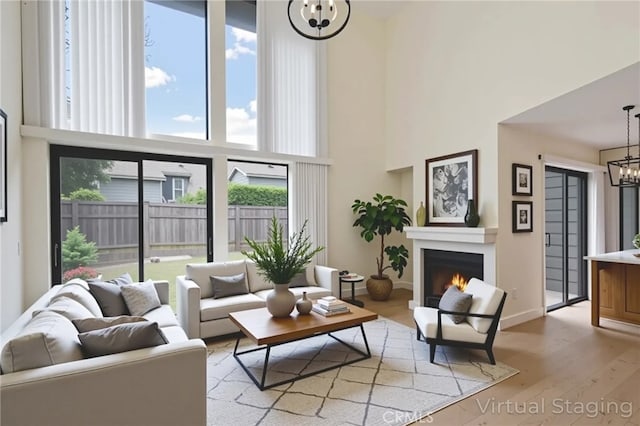 3350 M St Unit 33, Merced, CA 95348 - living area with a chandelier, a high ceiling, light wood-style floors, and a warm lit fireplace