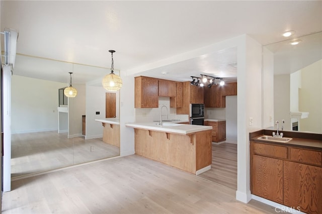 3350 M St Unit 33, Merced, CA 95348 - kitchen with a peninsula, a breakfast bar area, light wood-type flooring, pendant lighting, and brown cabinetry