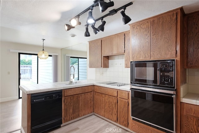 3350 M St Unit 33, Merced, CA 95348 - kitchen with black appliances, a peninsula, light wood finished floors, decorative backsplash, and a chandelier