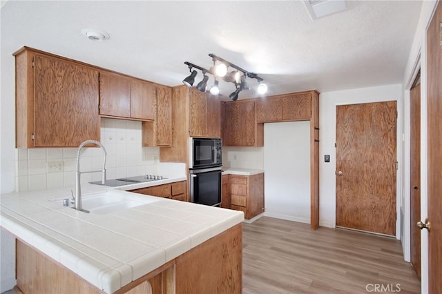 3350 M St Unit 33, Merced, CA 95348 - kitchen featuring black appliances, brown cabinetry, a peninsula, backsplash, and a textured ceiling