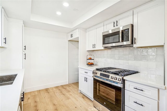 33871 Copper Lantern St, Dana Point, CA 92629 - kitchen featuring stainless steel appliances, light wood-type flooring, tasteful backsplash, a tray ceiling, and recessed lighting