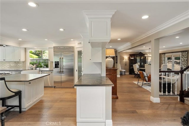 9911 Overhill Dr, North Tustin, CA 92705 - kitchen featuring stainless steel appliances, white cabinetry, a breakfast bar, backsplash, and recessed lighting