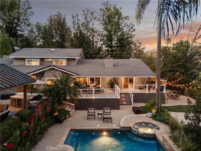 9911 Overhill Dr, North Tustin, CA 92705 - back of property at dusk featuring an in-ground hot tub, a chimney, an outdoor living space, a patio, and stucco siding