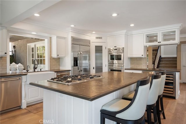 9911 Overhill Dr, North Tustin, CA 92705 - kitchen with appliances with stainless steel finishes, dark countertops, wine cooler, backsplash, and white cabinets