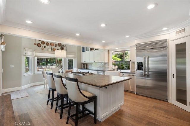 9911 Overhill Dr, North Tustin, CA 92705 - kitchen featuring stainless steel appliances, dark countertops, ornamental molding, decorative backsplash, and a kitchen island