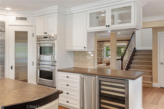 9911 Overhill Dr, North Tustin, CA 92705 - kitchen with double oven, beverage cooler, white cabinetry, dark countertops, and fridge
