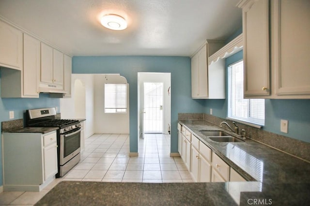 531 W 61st St, Los Angeles, CA 90044 - kitchen featuring stainless steel gas range oven, under cabinet range hood, dark countertops, and light tile patterned floors