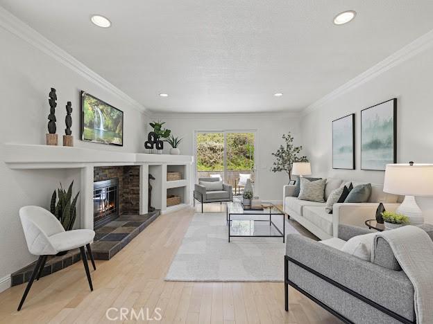 22601 Aguadero Pl, Saugus, CA 91350 - living area featuring crown molding, a glass covered fireplace, wood finished floors, and recessed lighting