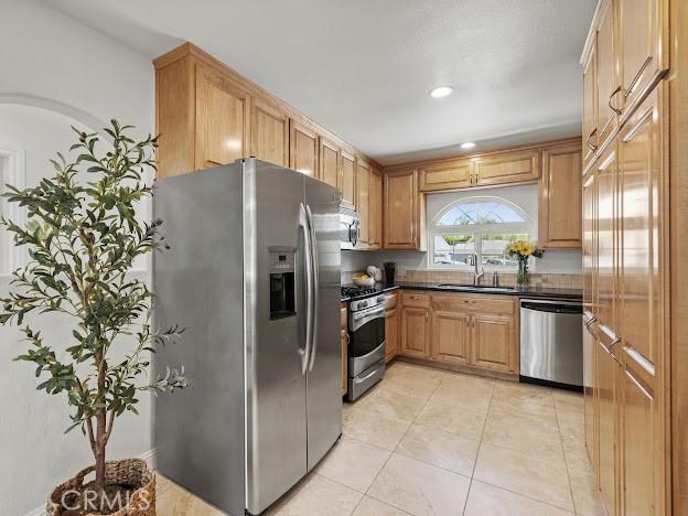 22601 Aguadero Pl, Saugus, CA 91350 - kitchen with stainless steel appliances, dark countertops, light tile patterned flooring, and recessed lighting