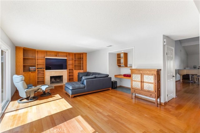 1317 Mill Creek Ct, Thousand Oaks, CA 91360 - living room with a tiled fireplace, light wood-style floors, a textured ceiling, and built in shelves