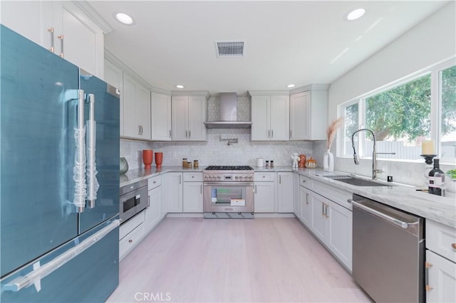16645 Holton St, La Puente, CA 91744 - kitchen with appliances with stainless steel finishes, wall chimney exhaust hood, backsplash, light stone countertops, and light wood-style floors