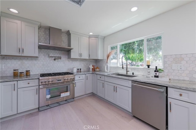 16645 Holton St, La Puente, CA 91744 - kitchen with appliances with stainless steel finishes, wall chimney range hood, recessed lighting, backsplash, and light wood-style flooring